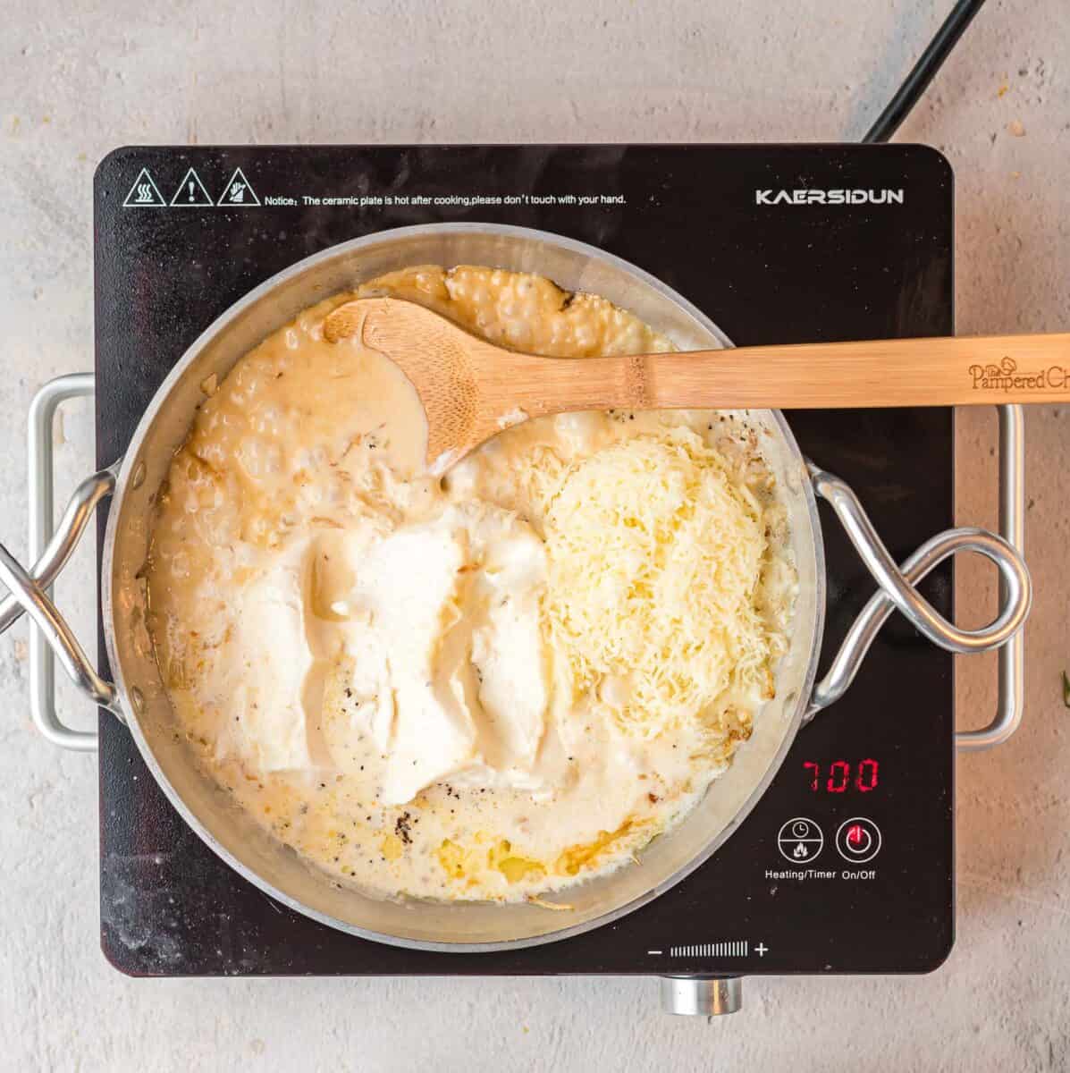 creamy ingredients are stirred together in a skillet with a wooden spoon.