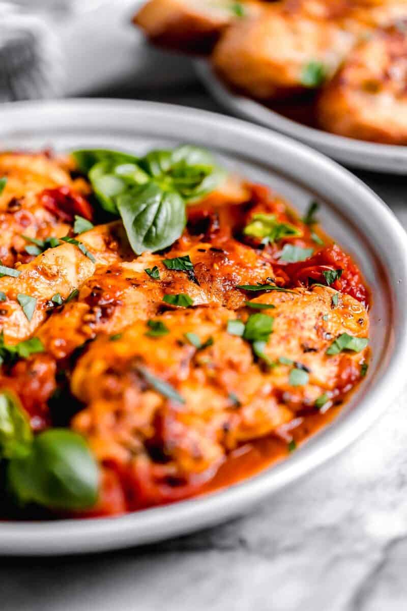 side view of cooked chicken tenders on a bed of tomato herb sauce