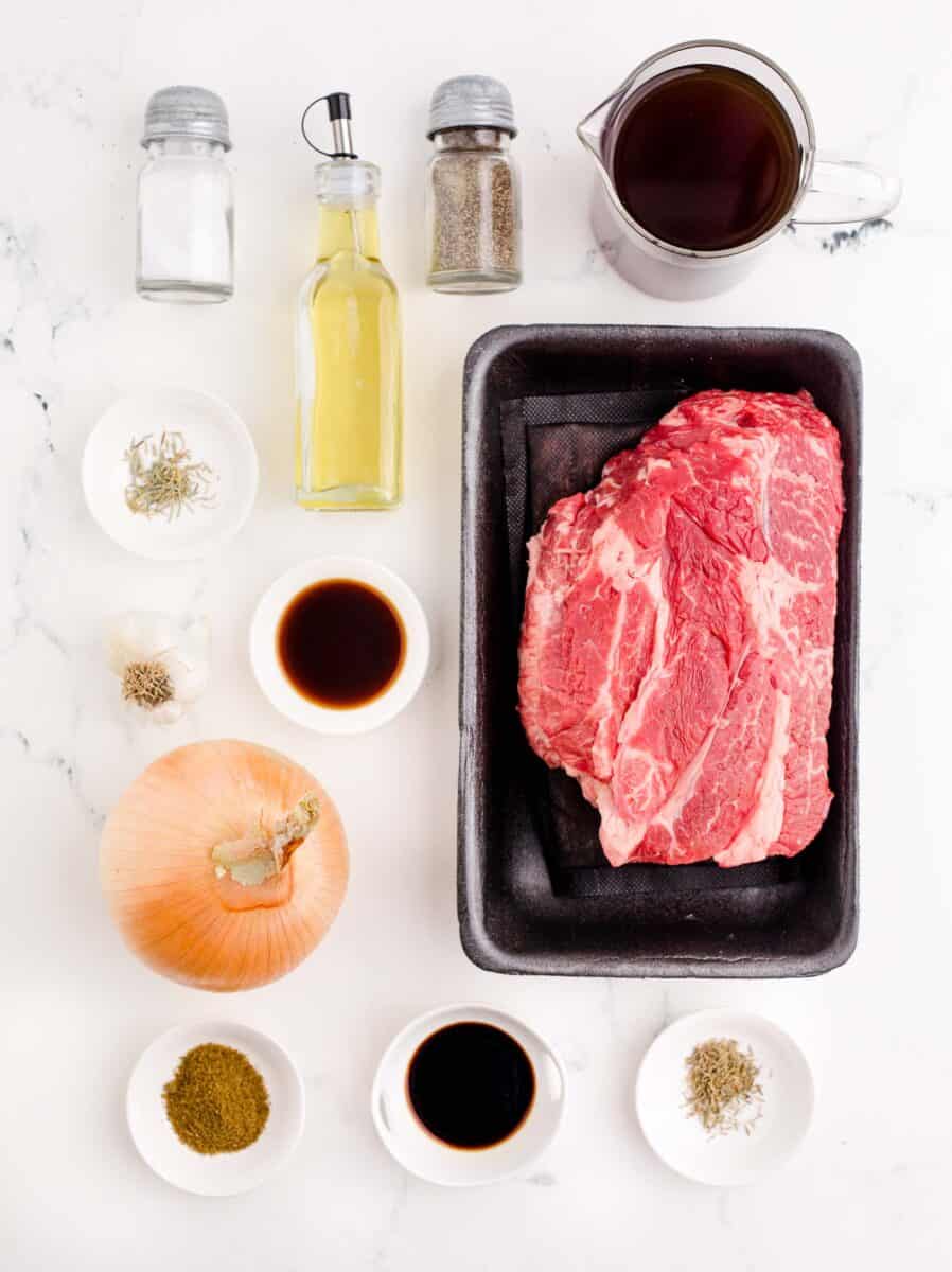 the ingredients for french dip sandwich are placed on a white surface.