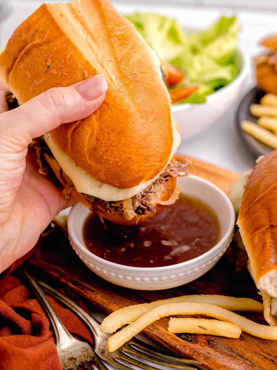 a sandwich is being dipped into au jus.