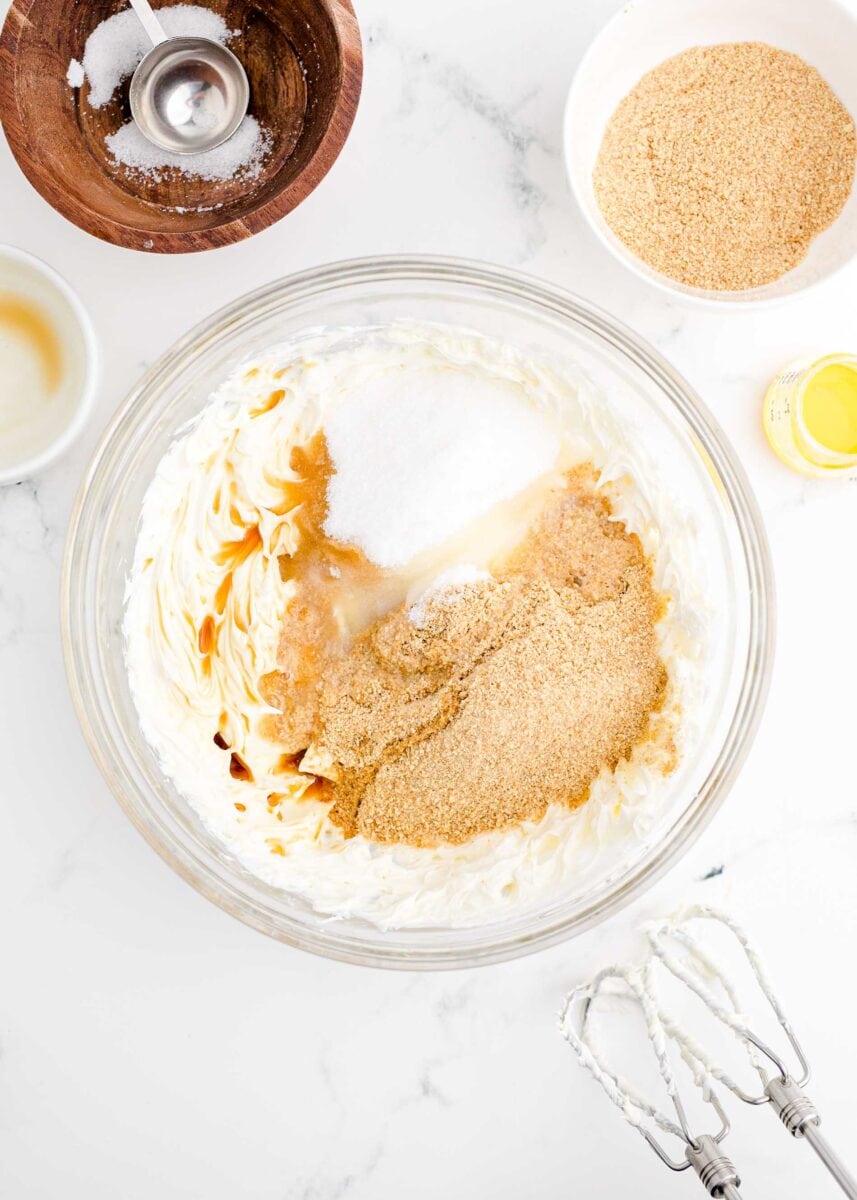 ingredients for cheesecake bites are placed in a large glass bowl.