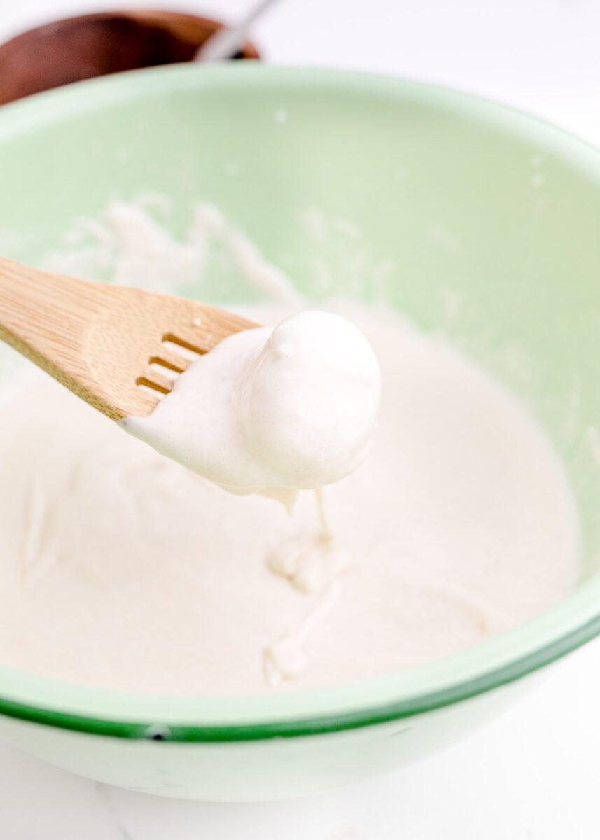 a creamy mixture is being stirred with a wooden spatula.