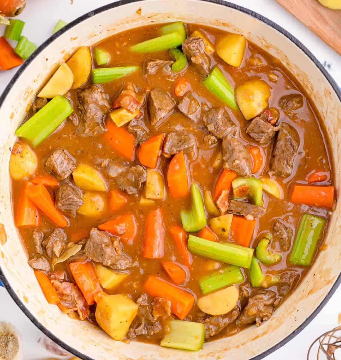 ingredients for guinness beef stew stirred together in a cast iron skillet