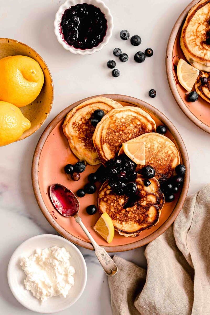 A serving of lemon ricotta pancakes is served with blueberry compote.