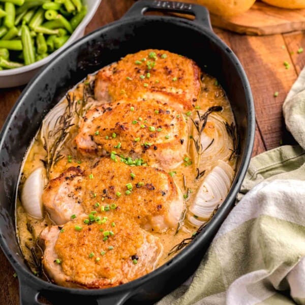 a tea towel is placed next to a pot filled with cooked pork chops.