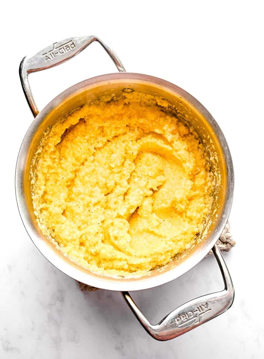 Cooked polenta in a pot after adding parmesan.