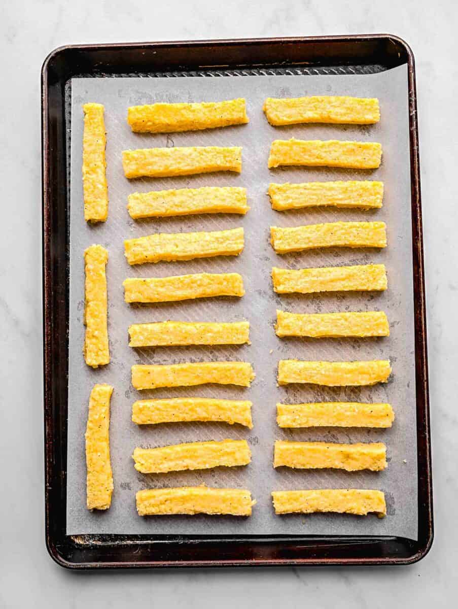 Polenta strips on a baking sheet lined with parchment paper ready to be baked.