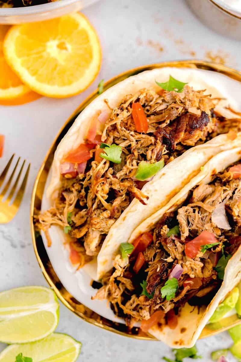 orange halves are placed next to a plate of tacos.