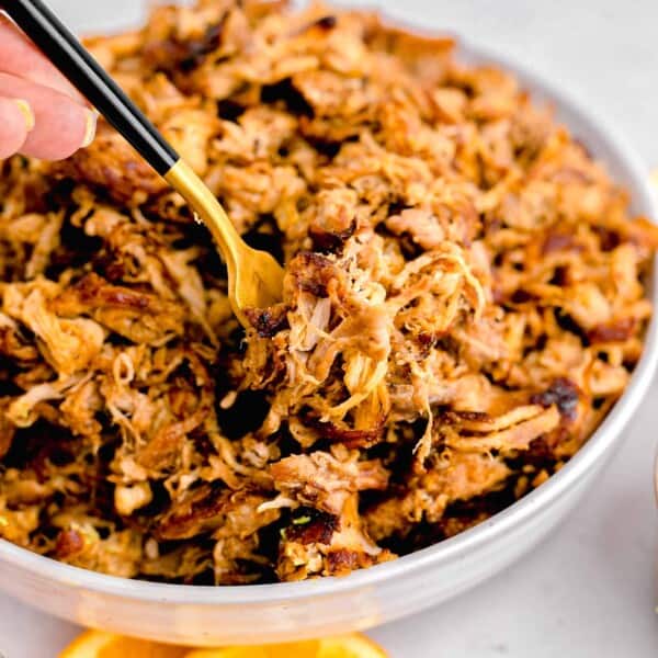 orange slices are placed next to a bowl of carnitas.