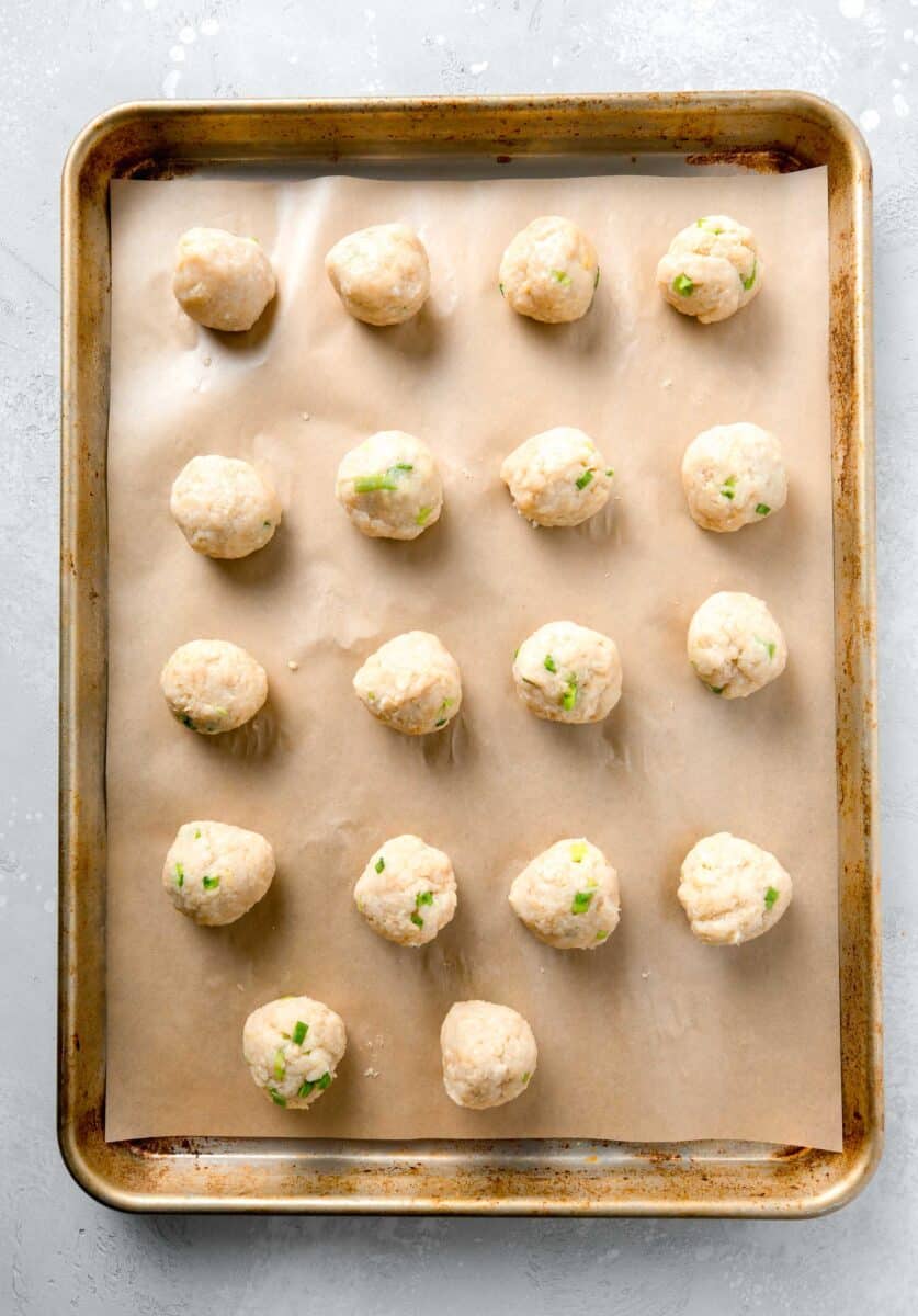 teriyaki turkey meatballs formed into meatballs on top of parchment paper on a rimmed baking sheet