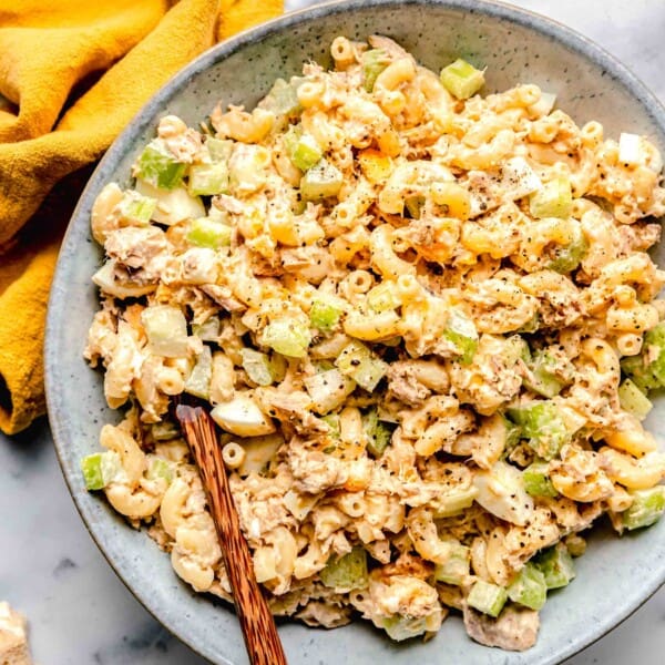 Tuna pasta salad in a bowl with a wooden spoon.