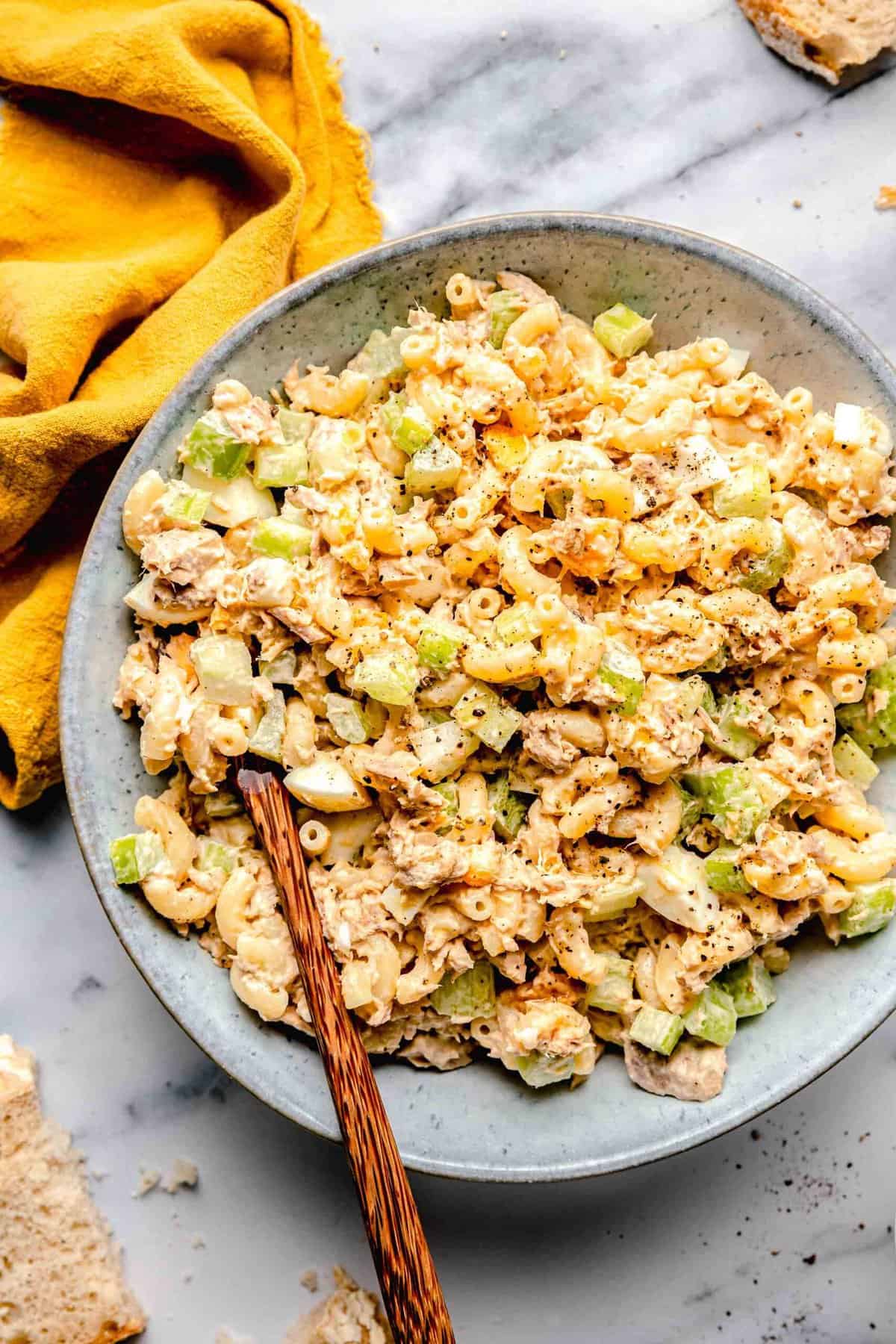 Tuna pasta salad in a bowl with a wooden spoon.