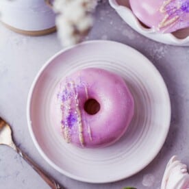 a frosted donut is placed on a round white plate