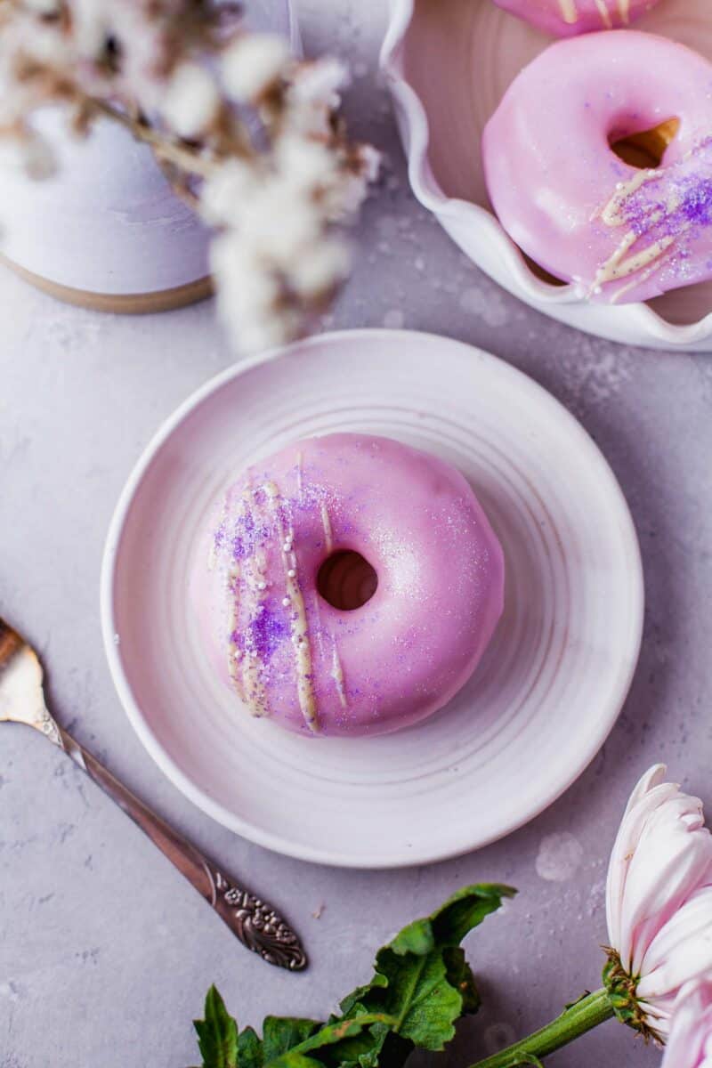a frosted donut is placed on a round white plate