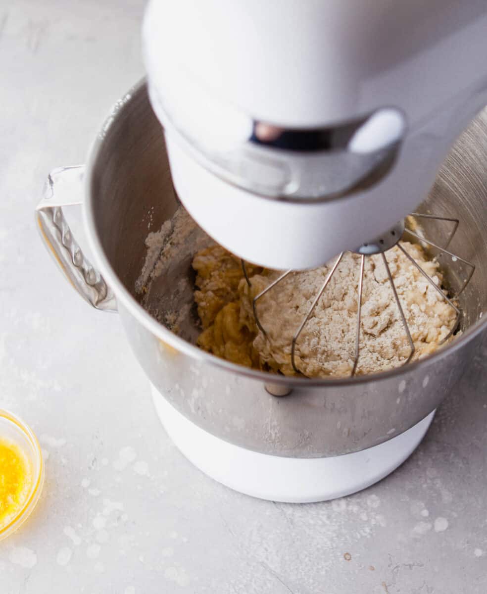 a stand mixer bowl is filled with ingredients for donuts