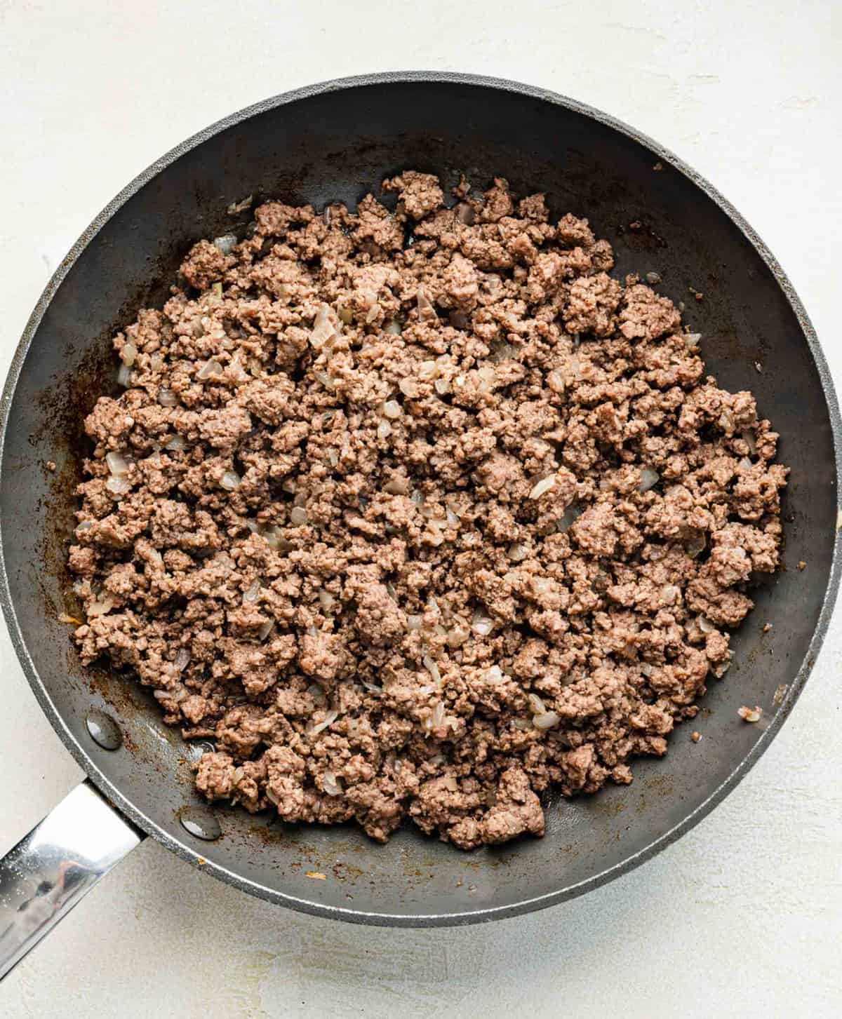 Browning ground beef with onions in a skillet.