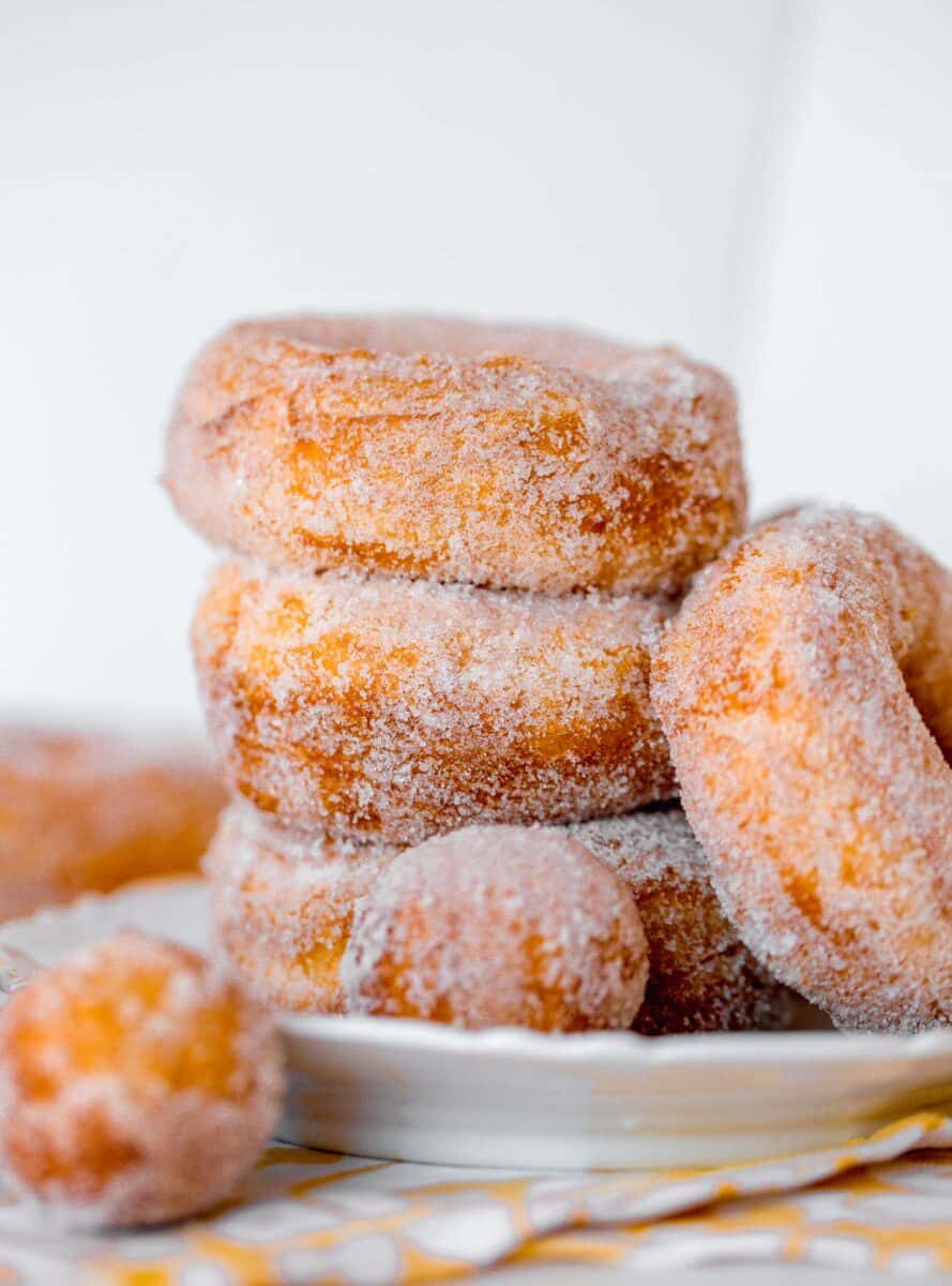 biscuit sugared donuts stacked on a plate with donut holes
