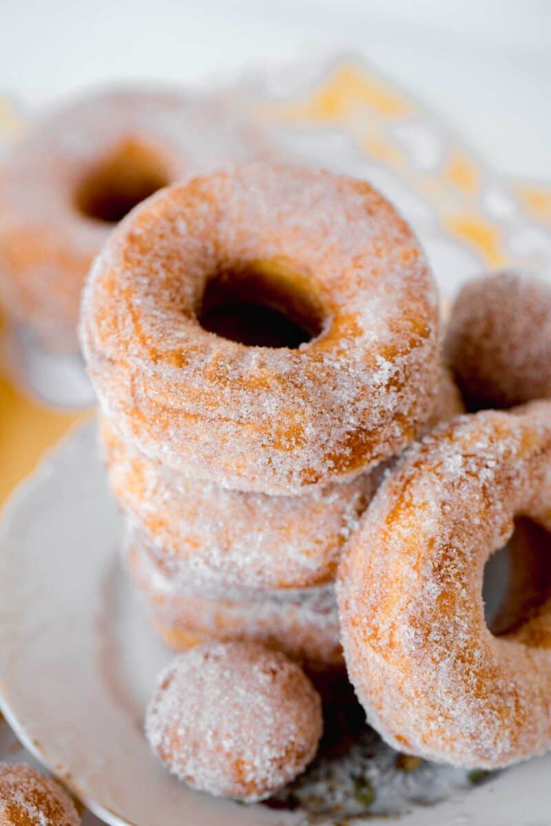 biscuit sugared donuts stacked on a plate with donut holes