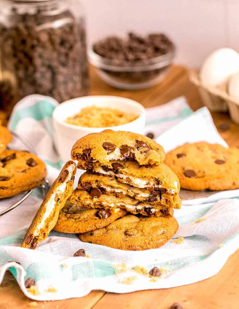 several cheesecake stuffed chocolate chip cookies are placed on top of a tea towel.