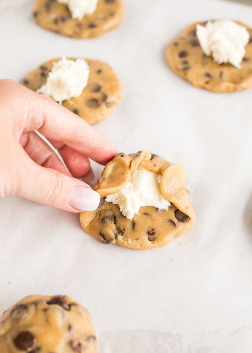 cookie dough is being formed around a cheesecake center.