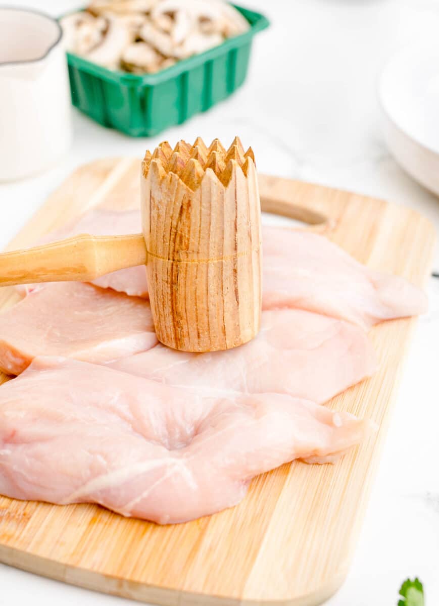 chicken is being pounded with a wooden mallet.