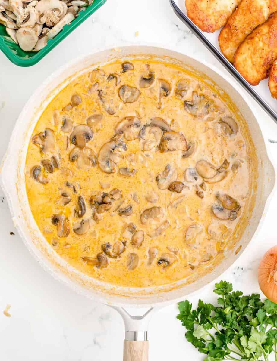 cream sauce and mushrooms are in a white skillet.