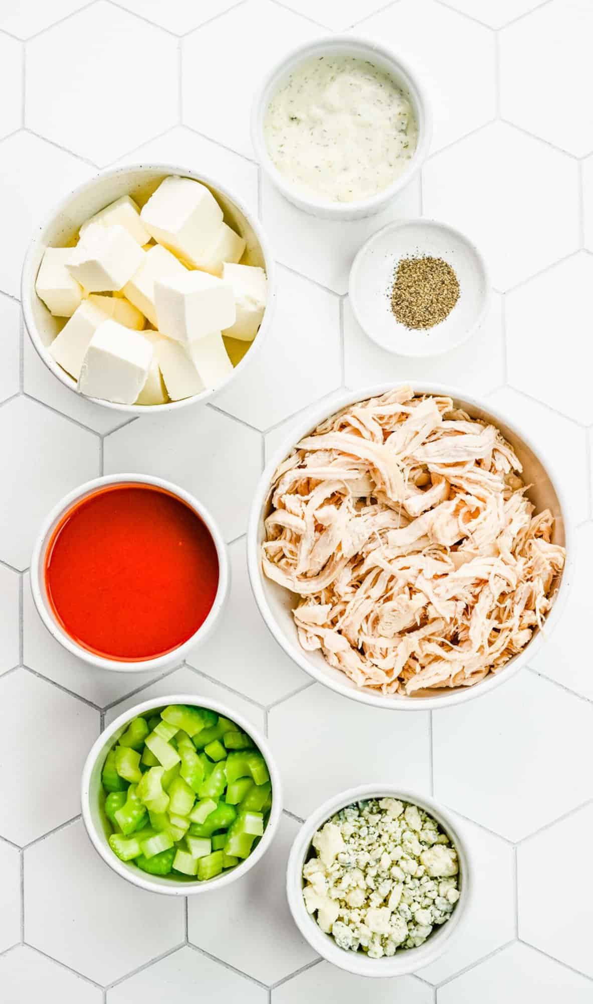 Ingredients for buffalo chicken dip separated into bowls.