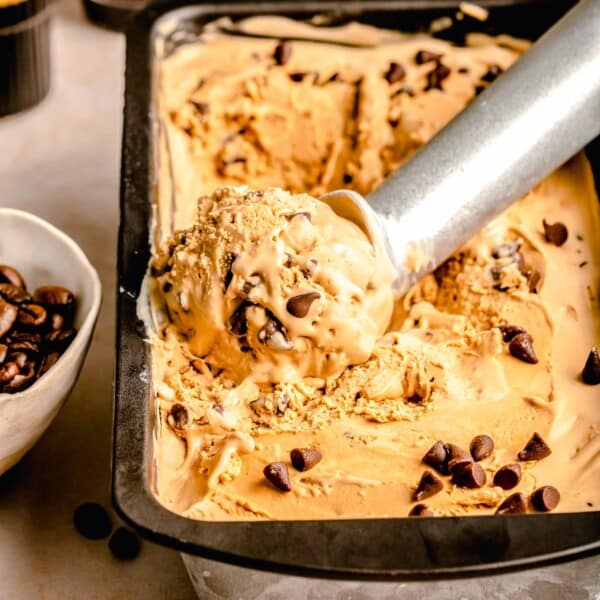 scoop of espresso chocolate chip ice cream on a metal ice cream scoop in a loaf pan