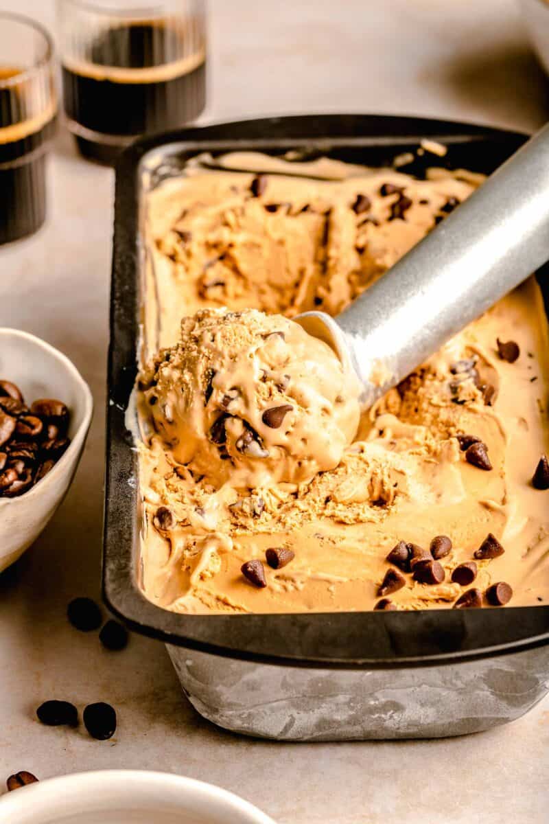 scoop of espresso chocolate chip ice cream on a metal ice cream scoop in a loaf pan