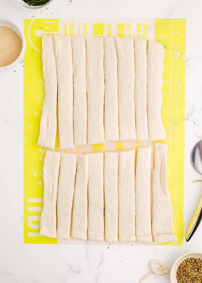 pizza dough is in the process of being cut into strips.