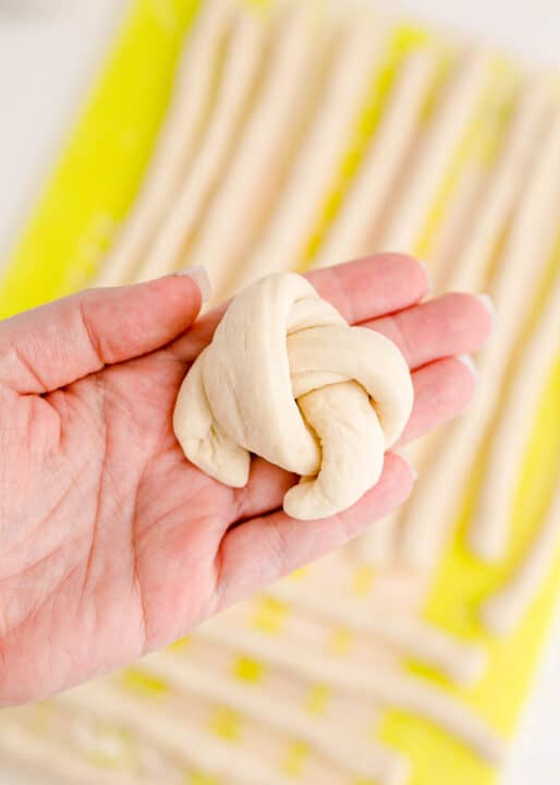 an unbaked garlic knot is placed in a hand.