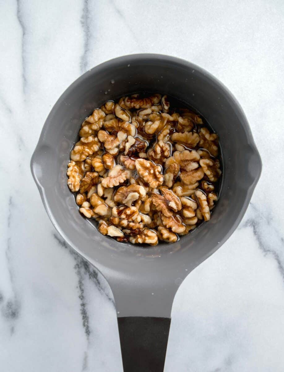 walnuts in a grey nonstick pot with sugar and water