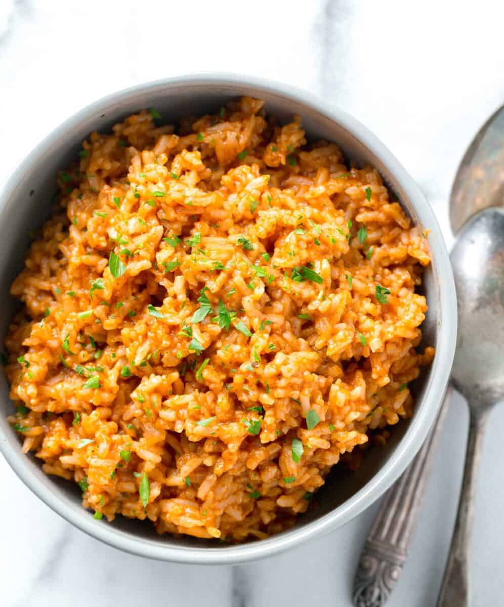 instant pot mexican rice with fresh parsley sprinkled top in a bowl next to two spoons