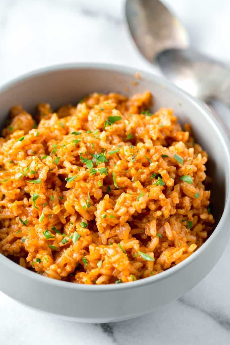 instant pot mexican rice with fresh parsley sprinkled top in a bowl next to two spoons