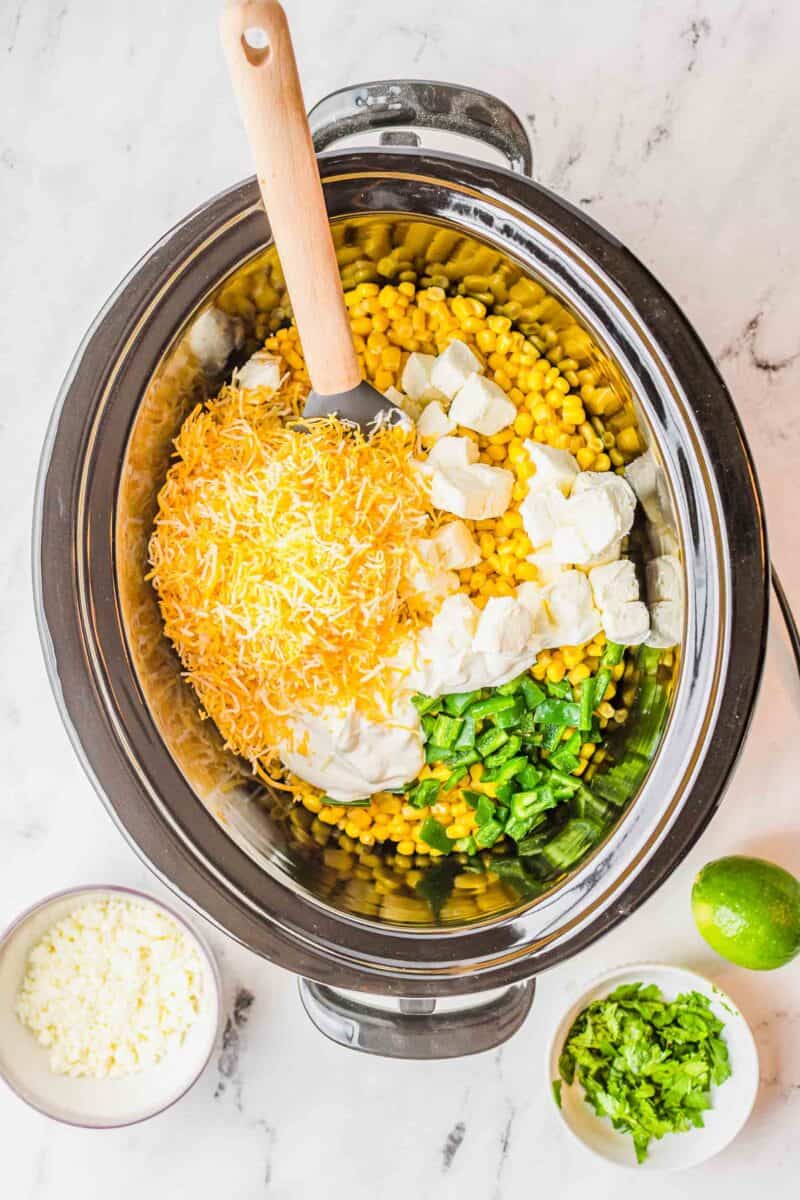 uncooked ingredients for jalapeno corn dip added to the insert of a slow cooker