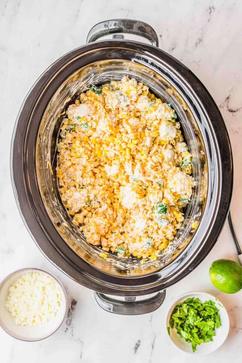 ingredients for jalapeno corn dip stirred together in the insert of a slow cooker