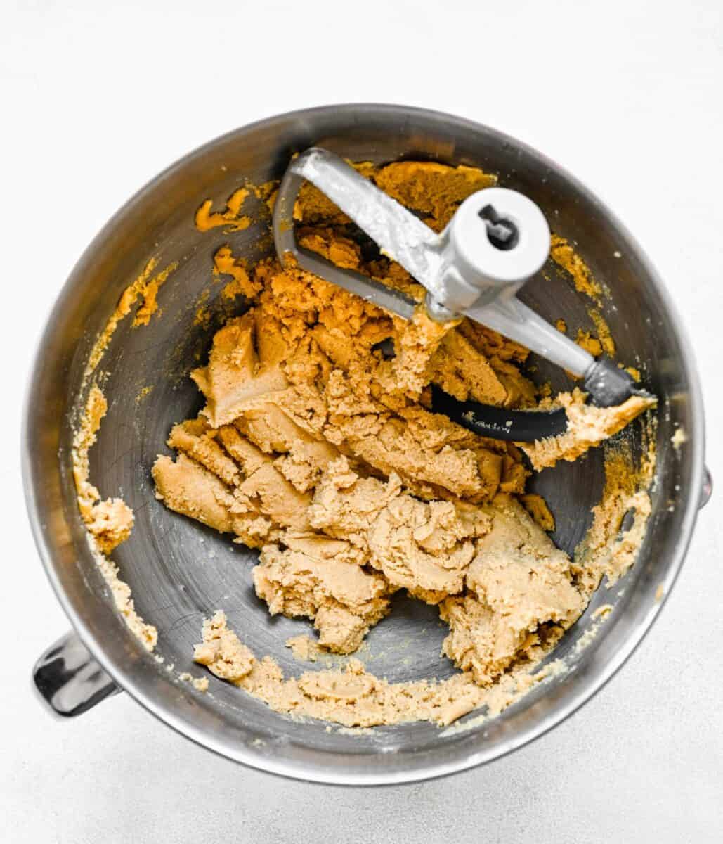 the electric mixer attachment is placed in a bowl of peanut butter cookie bar dough.
