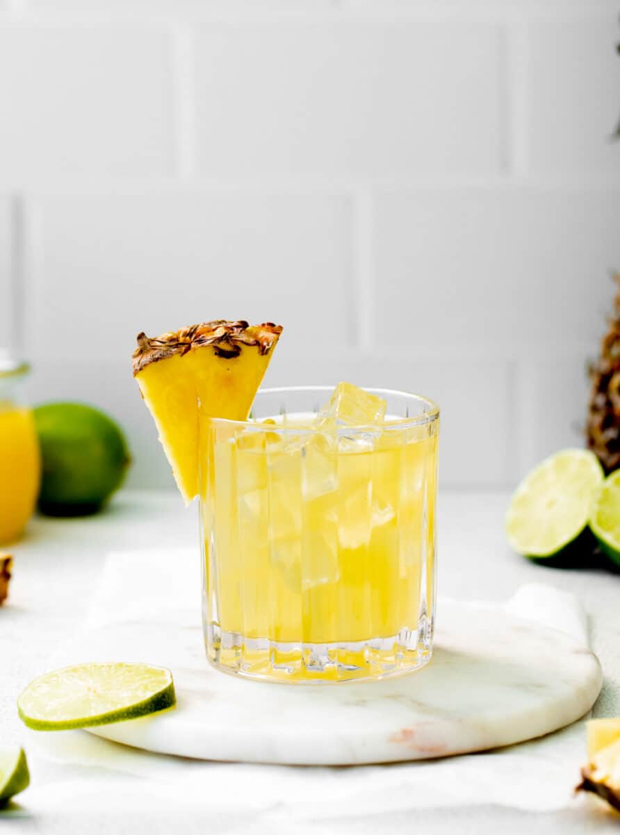 a wedge of pineapple is placed on the rim of a paloma glass.