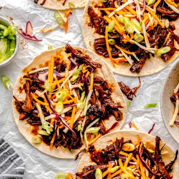 four tortillas are topped with pork and coleslaw.