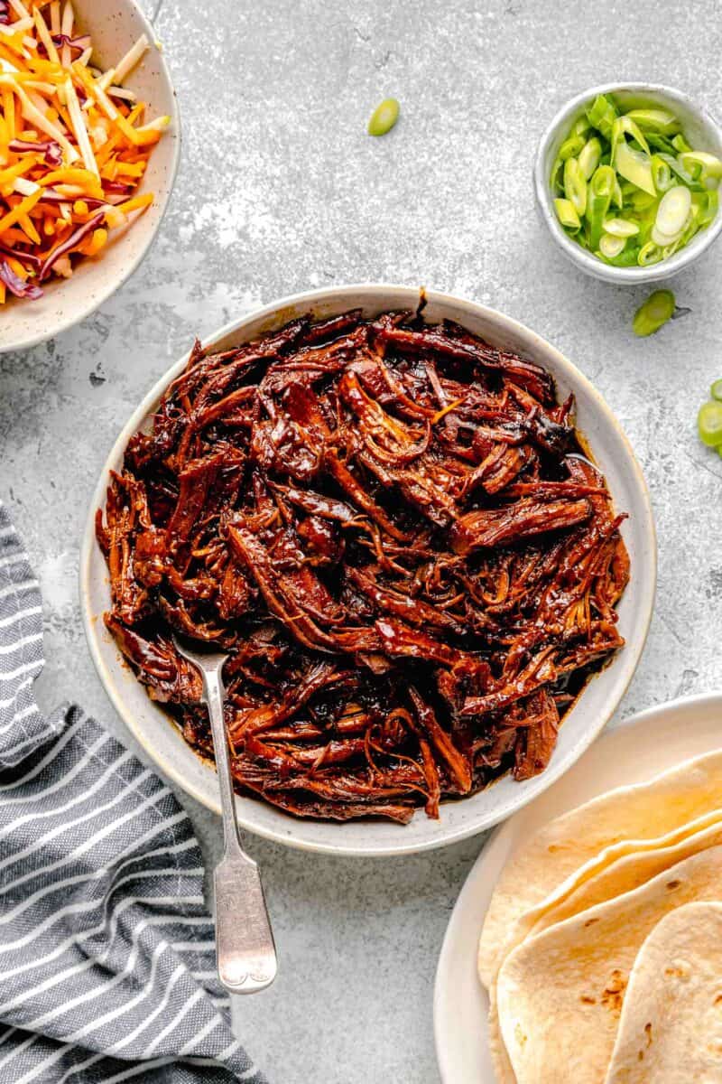 a white bowl is filled with shredded pork.