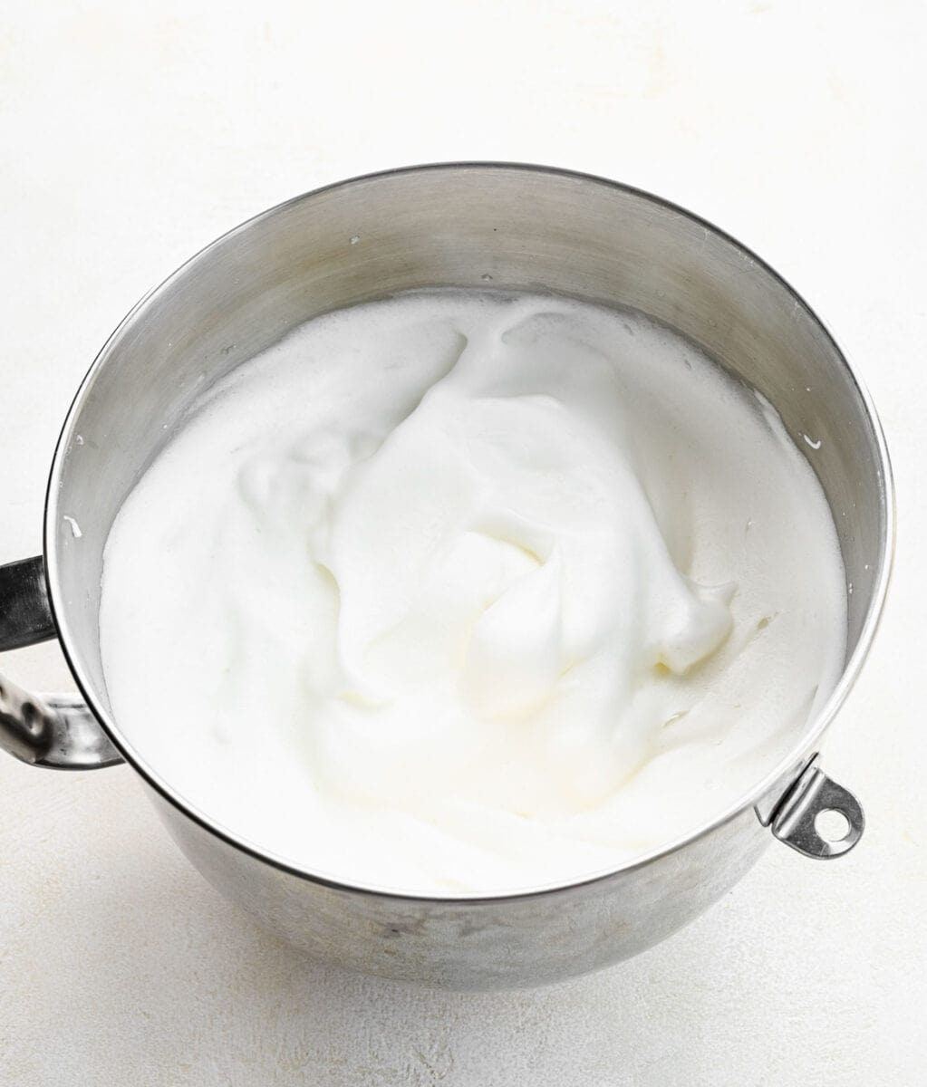 Egg whites whipped up with cream of tarter in a mixing bowl.