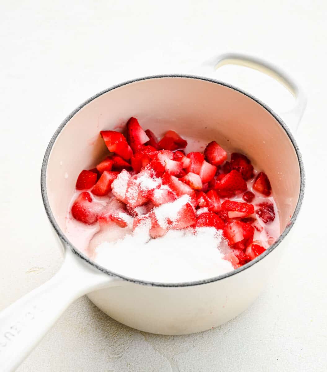 Adding strawberries, sugar, and lemon juice to water and cornstarch in a pot.