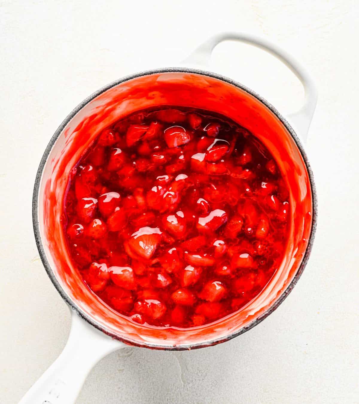 Cooking strawberry cake filling in a pot.