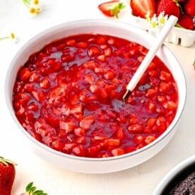 Strawberry cake filling in a bowl near fresh strawberries.