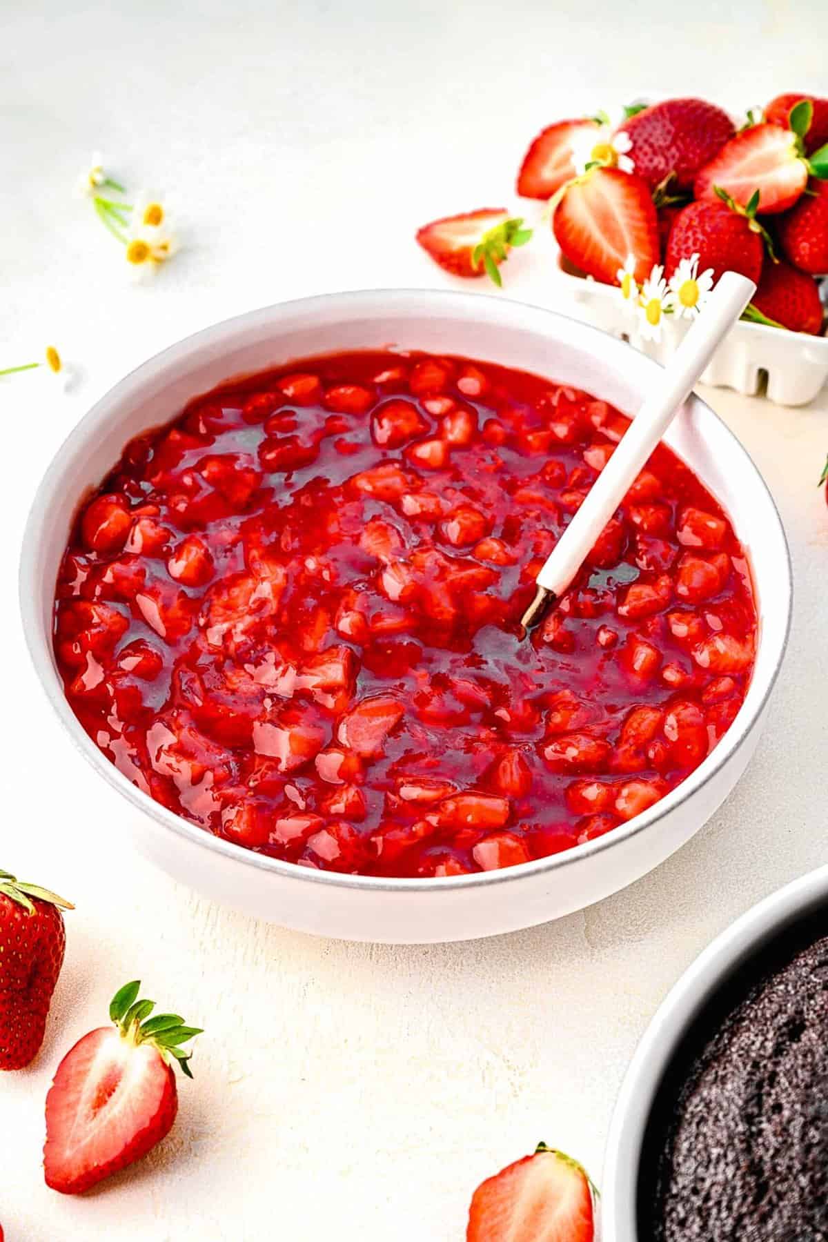 Strawberry cake filling in a bowl near fresh strawberries.