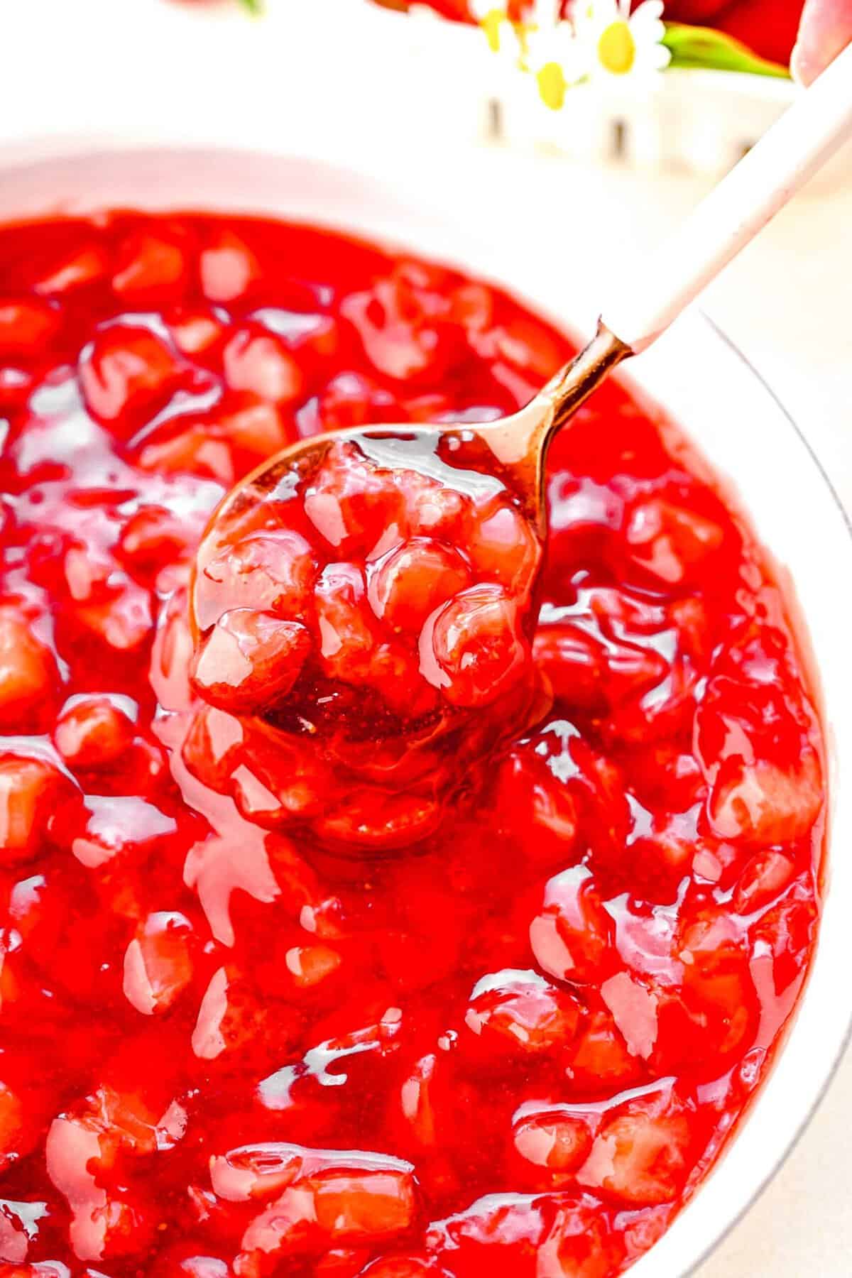 Taking a spoonful out of a bowl of strawberry cake filling.