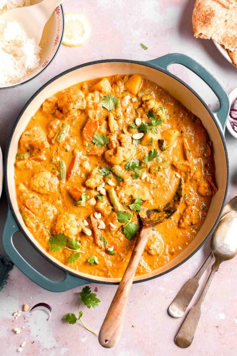 a large blue pot is filled with vegetable korma.