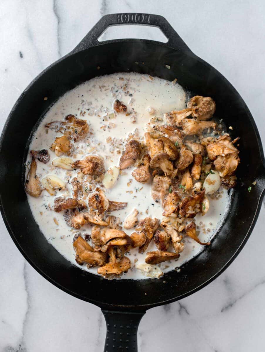 heavy cream added into a skillet with lions mane mushrooms, garlic, and onions