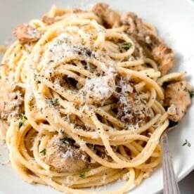 creamy lions mane pasta in a white bowl with a metal fork