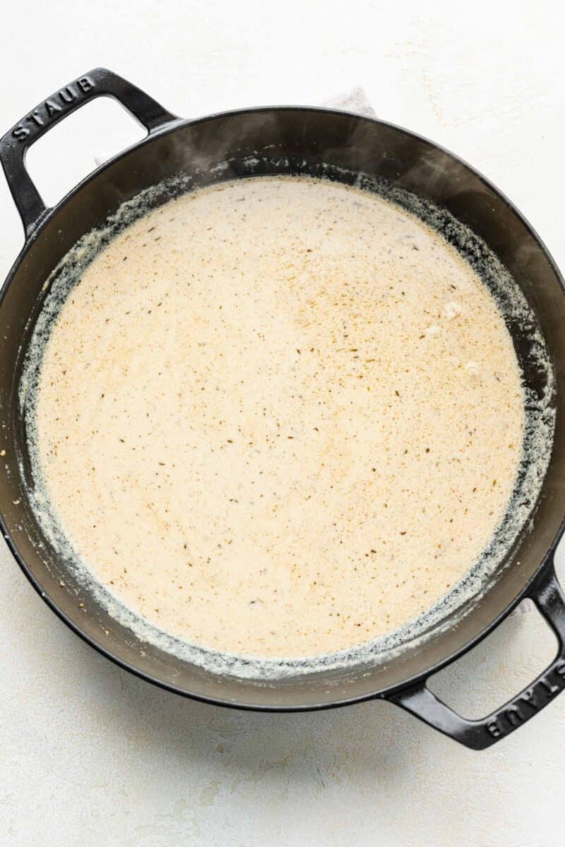 cream sauce is being cooked in a pan